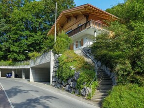Una casa de dos pisos con una escalera de piedra que conduce a una terraza de madera.