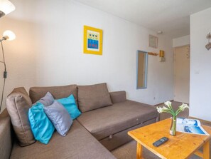 A modern living room with a brown sofa, a wooden coffee table, and a remote control.