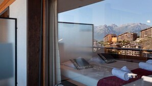 Ett hotellrum med en säng, ett fönster och utsikt över bergen.