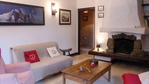 Un salon chaleureux avec un canapé, une table basse en bois, une cheminée et un tableau accroché au mur.
