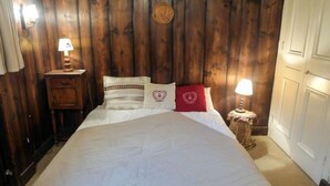 Un grand lit avec une literie blanche, une tête de lit en bois et deux tables de chevet avec des lampes.