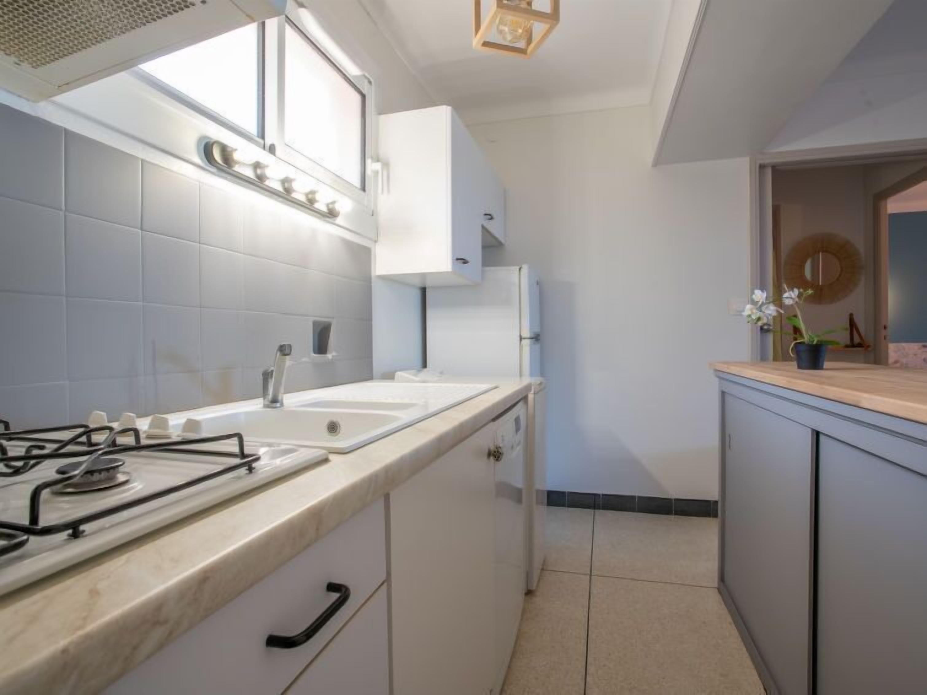 A modern kitchen with white cabinets, a gas stove, a sink, and a window above the counter.