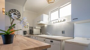 Eine moderne Küche mit Holzarbeitsplatte, weißen Schränken, einem eingebauten Backofen und einem Fenster über der Spüle.
