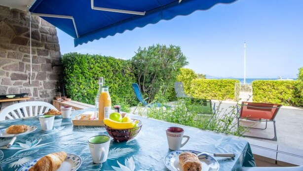 Ein Essbereich im Freien mit einem für das Frühstück gedeckten Tisch, darunter Croissants, eine Fruchtbowl und eine Saftflasche.
