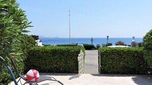 Ein Weg, der zum Strand führt, mit Blick auf das Meer und die Berge.