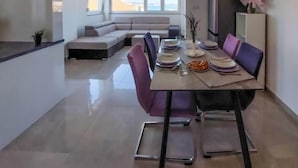 A modern dining area with a table set for four, a sofa in the background, and a view of the sea through large windows. - Sun seeker by Interhome (Brodarica)