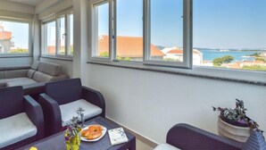 A balcony with a view of the sea, wicker furniture, and a table with a plate of food and a vase of flowers. - Sun seeker by Interhome (Brodarica)
