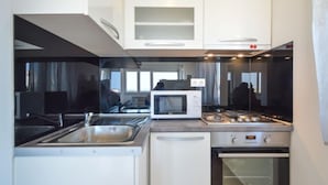 A compact kitchen with a microwave, stove, sink, and oven. - Sun seeker by Interhome (Brodarica)