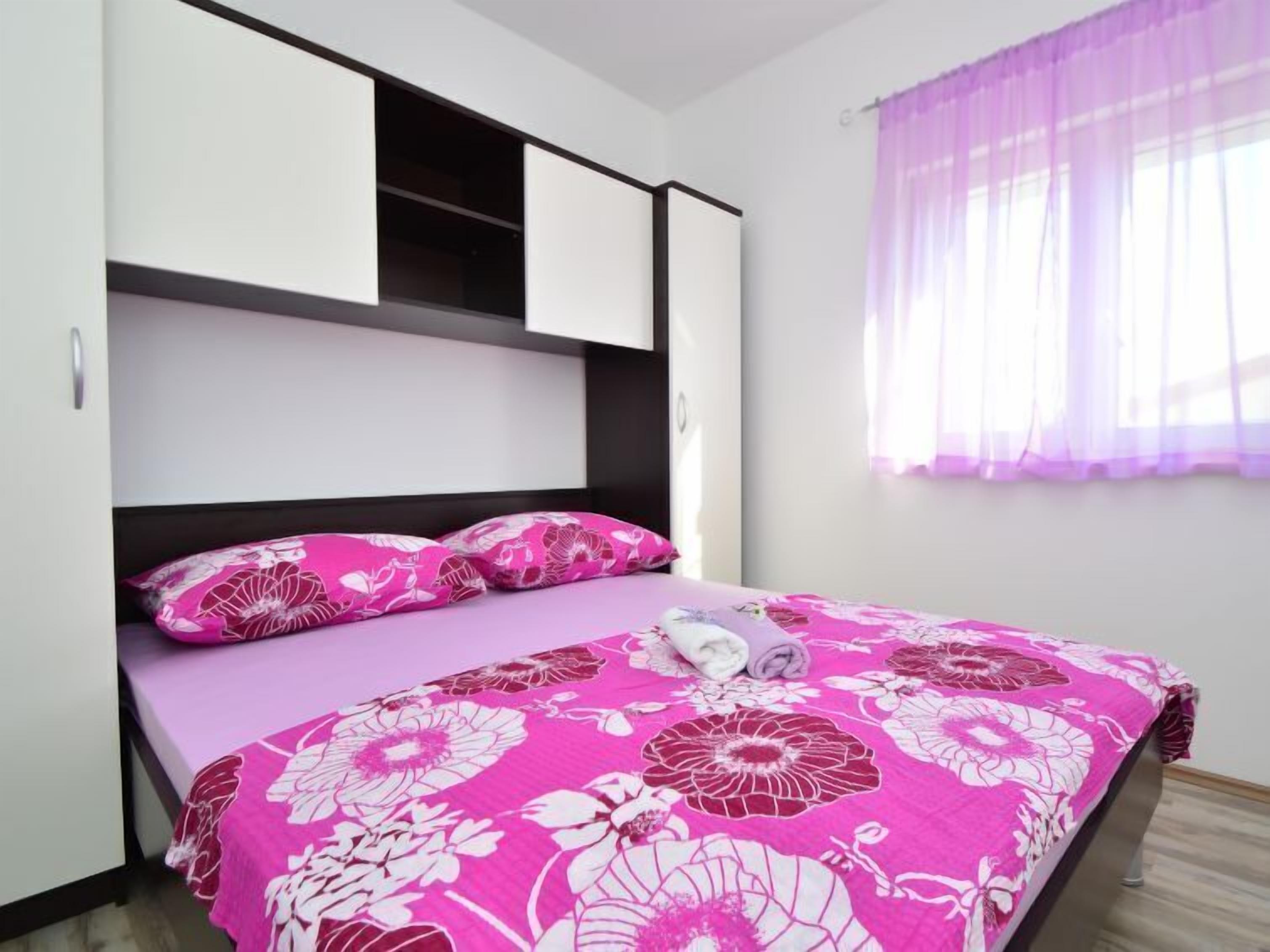 A bedroom with a bed, a wardrobe, and a window with curtains.