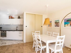 A modern kitchen with white cabinets, a built-in oven, and a dining area with a white table and chairs. - Cadet Rousse by Interhome (Le Lavandou)