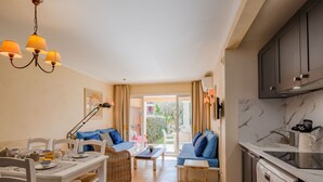 A compact living space with a dining area, a sofa, a kitchen, and a view to the outside. - Les Rivages des Issambres by Interhome (Les Issambres)