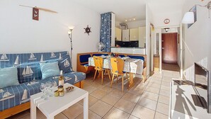 Ein Wohnzimmer mit einer Couch, einem Esstisch und einer Küche im Hintergrund.
