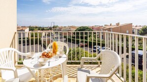 A balcony with a table set for breakfast, including a glass of orange juice, bowls, and plates of food. - Hameau de Pech I by Interhome (Cap d'Agde)