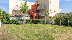 A modern apartment building with a central staircase, surrounded by a well-maintained lawn and greenery. - Hameau de Pech I by Interhome (Cap d'Agde)
