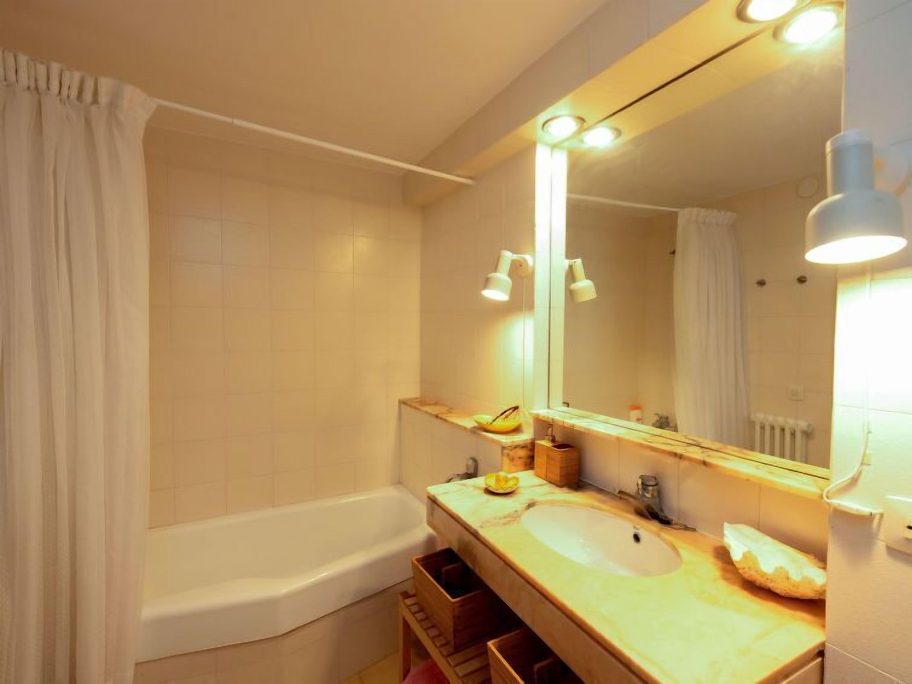A bathroom with a bathtub, a sink, a mirror, and a towel rack.