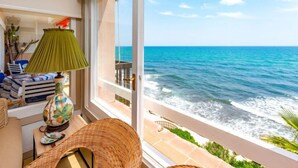 A room with a view of the ocean, a green lamp, and a wicker chair.