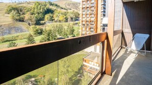 Un balcó amb vista a una vessant de muntanya i un edifici d'altes plantes.