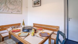 Una taula de dinar amb caires, un mapa a la paret i una porta a la dreta.