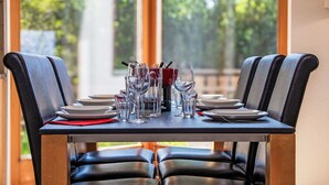 Mesa de comedor dispuesta para cuatro personas, con sillas, vasos y cubiertos.