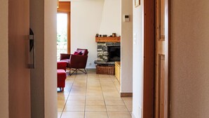 Un pasillo que conduce a una sala de estar con chimenea, sillas rojas y piso de baldosas.