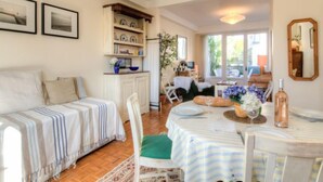 Une pièce confortable avec un lit, une table à manger dressée pour deux personnes et un petit coin cuisine.