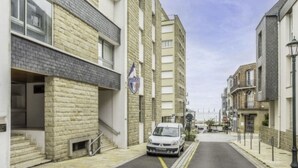 Une rue étroite bordée d’immeubles d’habitation, un panneau de signalisation de la police et une voiture garée.