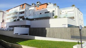 Un moderno edificio residenziale a più piani con balconi, tetto piano e recinzione in legno.