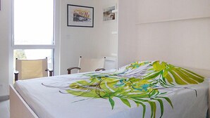 Una camera da letto con un letto, una sedia, una finestra e due quadri appesi al muro.