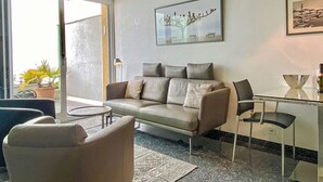 A modern living room with a sofa, chairs, a glass table, and a painting on the wall. - Lakeview App 501 by Interhome (Ascona)