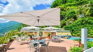 An outdoor patio with a pool, surrounded by lush greenery and mountains. - Lakeview App 501 by Interhome (Ascona)
