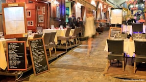 Ein Essbereich im Freien mit gedeckten Tischen, ausgelegten Speisekarten und einem Schild für das Restaurant 'Le Marais'.