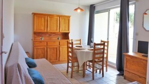 Ein gemütliches Zimmer mit einem Bett, einem Esstisch mit Stühlen, Holzschränken und einem Fernseher.