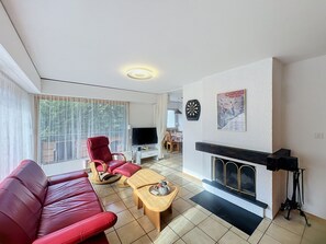 A living room with a red sofa, a wooden coffee table, a fireplace, and a television. - Diana E2 by Interhome (Nendaz)