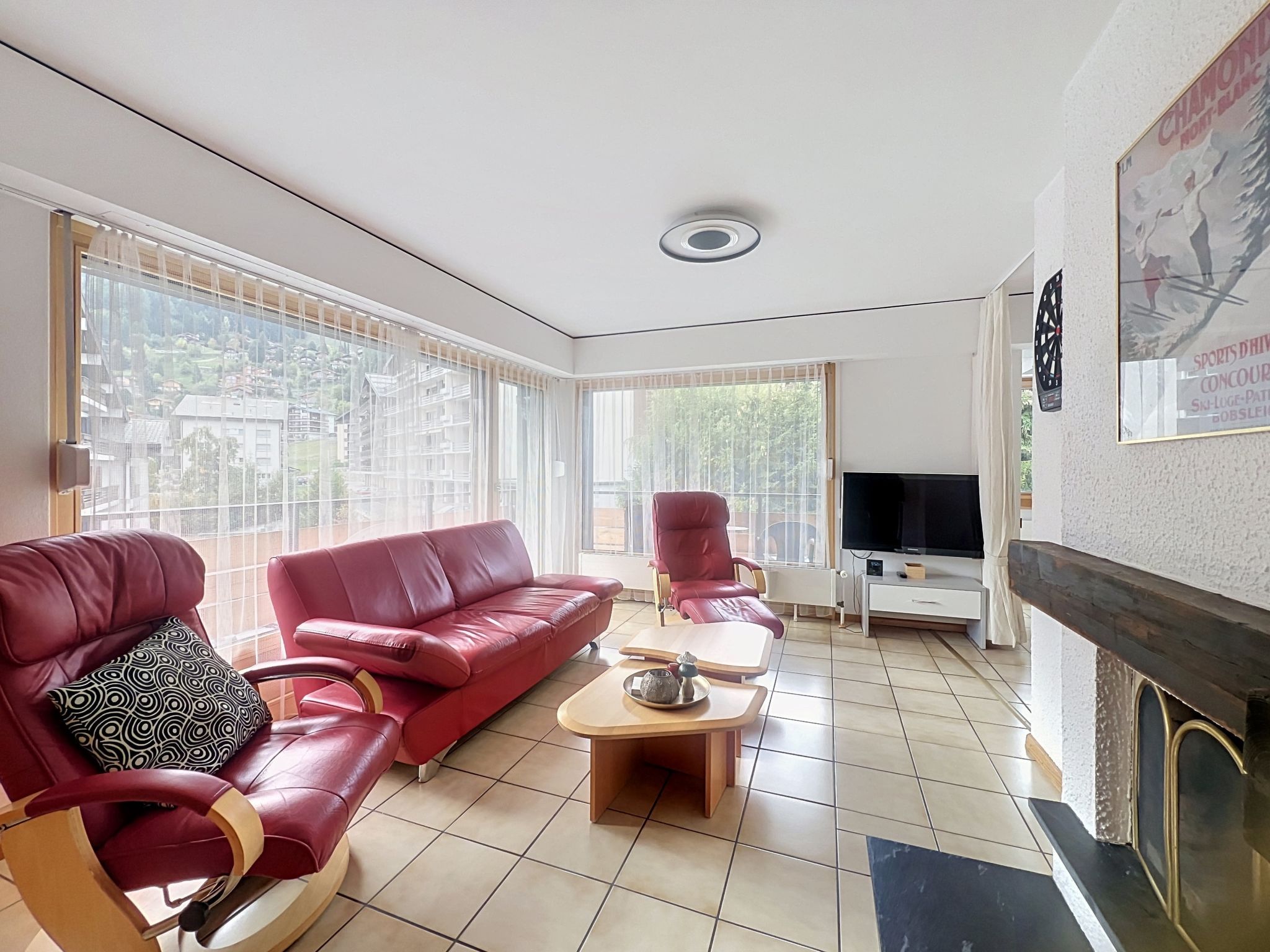 A living room with a red sofa, a red armchair, a television, and a fireplace.