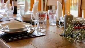 Una mesa de comedor con platos, vasos y una vela, con una botella y flores sobre la mesa.