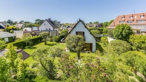 Een woonwijk met huizen, verzorgde tuinen en een heldere lucht.