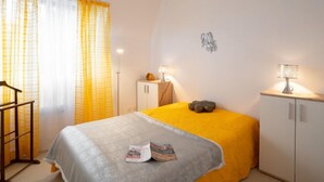 Een slaapkamer met een bed, nachtlampjes, een klein kastje en een decoratief wandobject.
