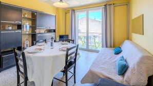 Un espace de vie compact comprenant un coin repas, une kitchenette et un balcon avec vue.