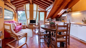 A cozy cabin interior with a wooden ceiling, a dining area with a round table and chairs, a kitchen with white cabinets, and a living area with a sofa and chairs. - Chez Les Roset by Interhome (Arvier)