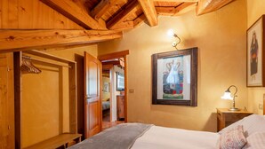 A bedroom with a wooden ceiling, a bed with white linens, a nightstand with a lamp, and a framed picture on the wall. - Chez Les Roset by Interhome (Arvier)