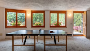 A room with a ping pong table, wooden flooring, and large windows with flower boxes. - Chez Les Roset by Interhome (Arvier)
