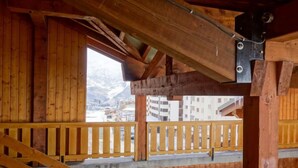 Un balcon en bois offrant une vue sur une montagne enneigée et des bâtiments.