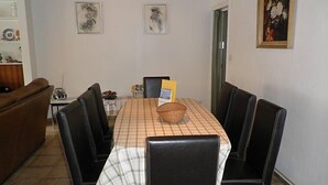Ein Essbereich mit einem für vier Personen gedeckten Tisch, umgeben von schwarzen Stühlen. An der Wand über dem Tisch hängen zwei gerahmte Kunstwerke.