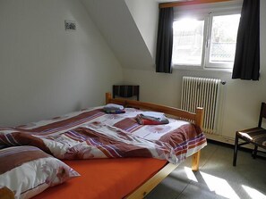 En säng för en person med ett blommigt överkast, ett element och ett fönster med gardiner.
