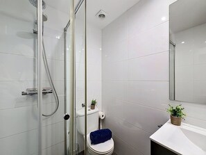 Une salle de bain moderne avec une douche à parois de verre, des toilettes et un lavabo avec un miroir.