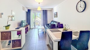 Una sala moderna con sofá, mesa de comedor y un reloj en la pared.