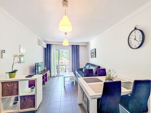 A modern living room with a sofa, dining table, and a clock on the wall.