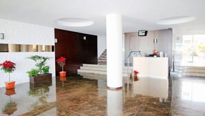 Un hall d’entrée spacieux, doté d’un sol en marbre, d’un comptoir de réception et d’un escalier menant aux étages supérieurs.
