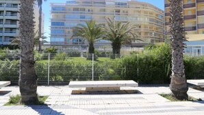 A modern multi-story building with balconies, surrounded by palm trees and a metal fence. - Copacabana by Interhome (Canet-Plage)