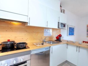 A compact kitchen with white cabinets, a microwave, a sink, and a stove. - Cap Ras by Interhome (Llançà)